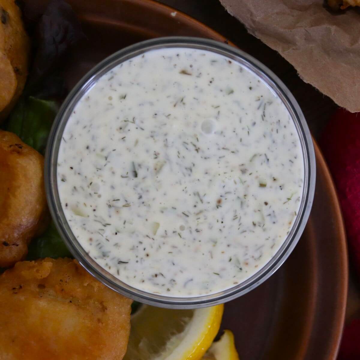 Creamy white old-fashioned southern tartar sauce in a small bowl, with herbs visible in it.