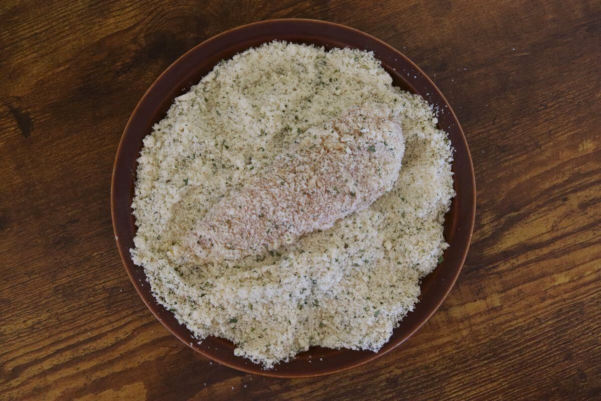 Chicken tender coated in almond breadcrumb mixture on a plate.