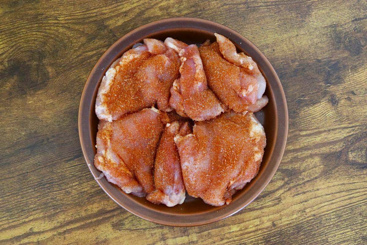 Seasoned boneless chicken thighs arranged on a plate.