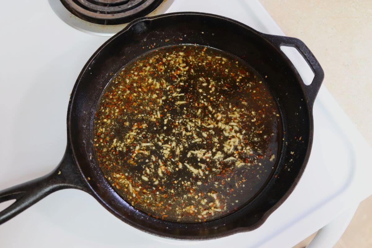 Honey, soy sauce, garlic, and red pepper flakes in a cast iron skillet on a stovetop.