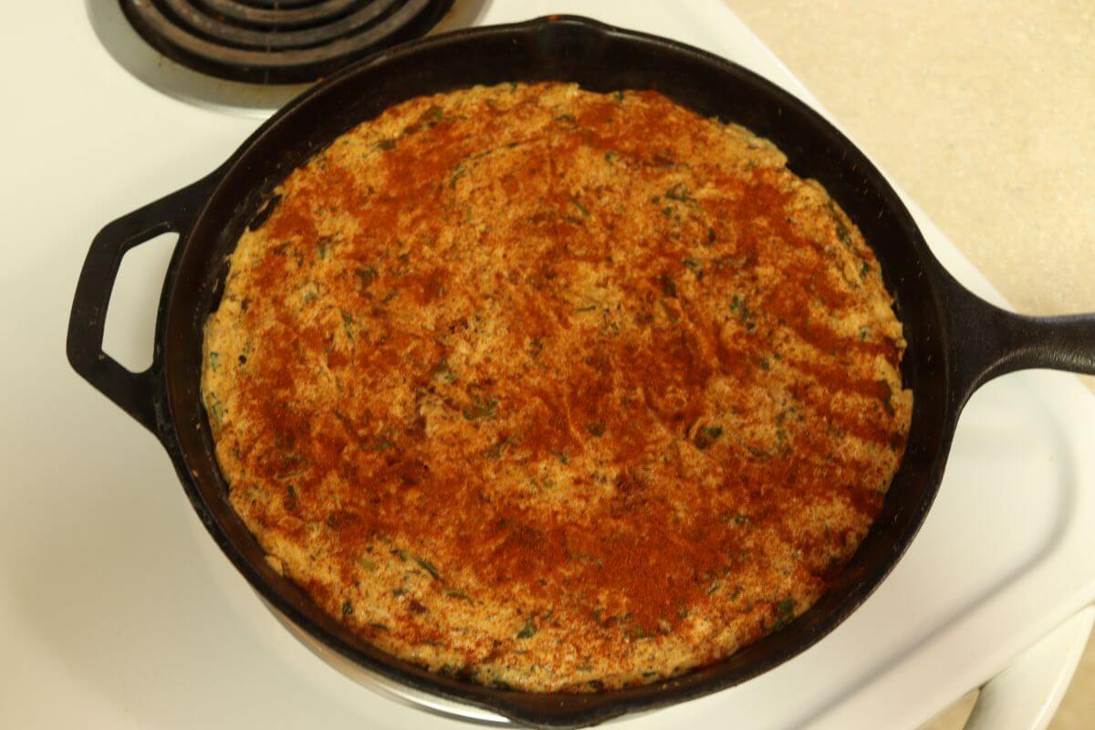Baked chicken dip with paprika on top in cast iron skillet.