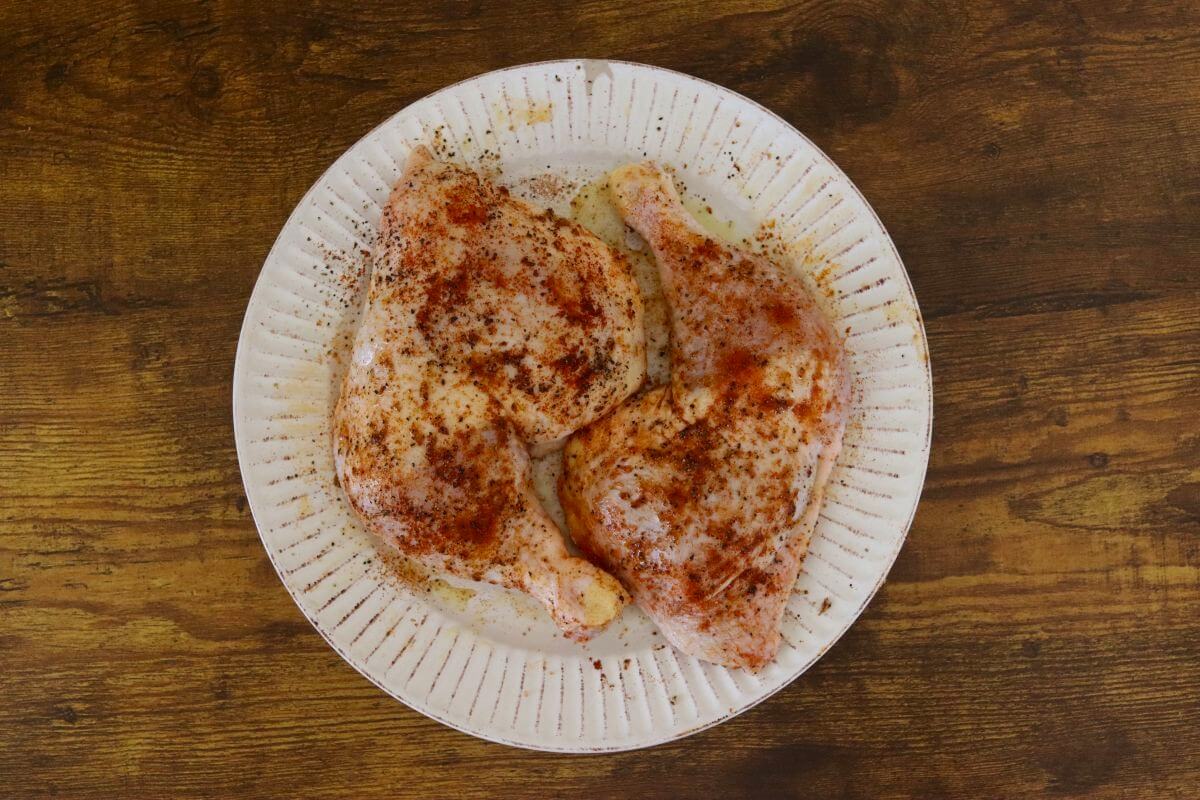 Raw chicken leg quarters seasoned with paprika, garlic, salt, and pepper.