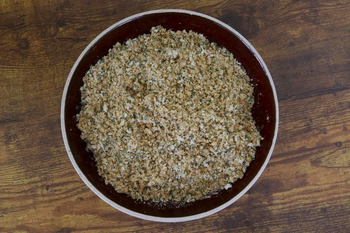 Bowl filled with a mixed breadcrumb topping on a wooden surface.