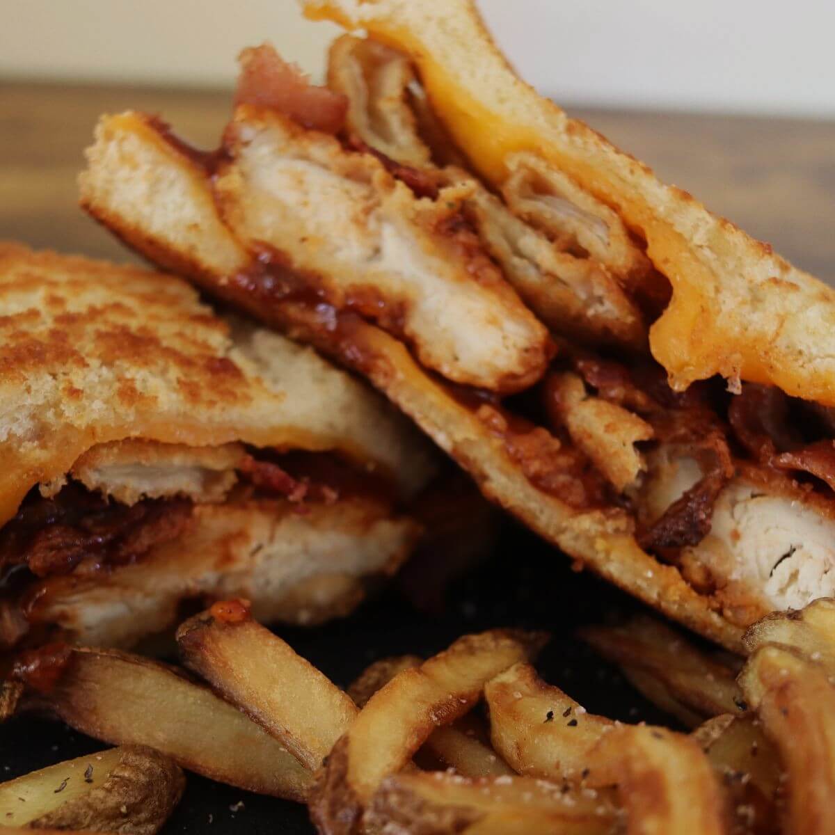 Chicken, bacon, and melted cheese inside grilled sandwich halves with fries.