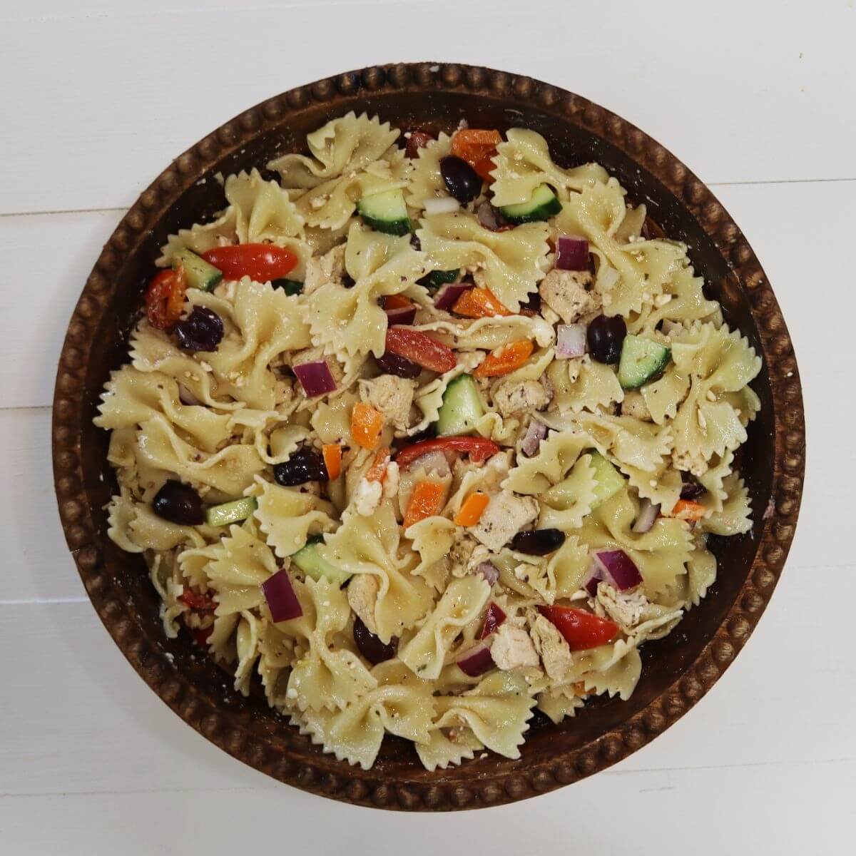 Farfalle pasta salad with chicken, cucumber, tomatoes, olives, red onion, and feta cheese.
