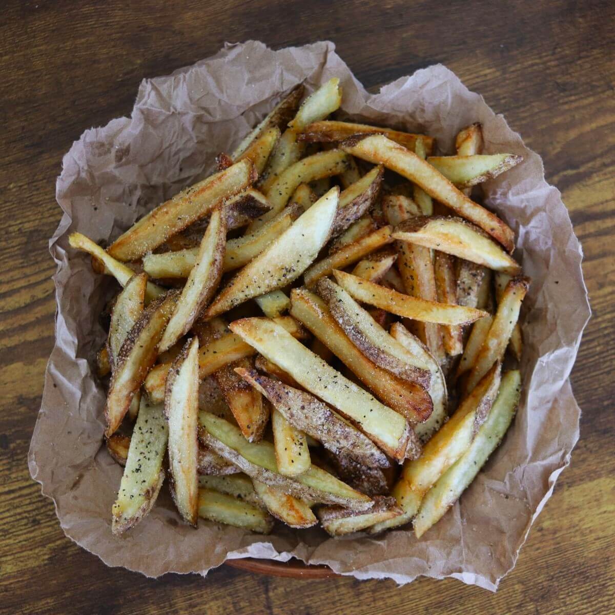 Basket lined with parchment paper filled with seasoned hand cut french fries.