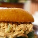 Spicy chicken salad sandwich on a bun with lettuce, text overlay reading “Spicy Chicken Salad Sandwich Creamy, Spicy & Crunchy".