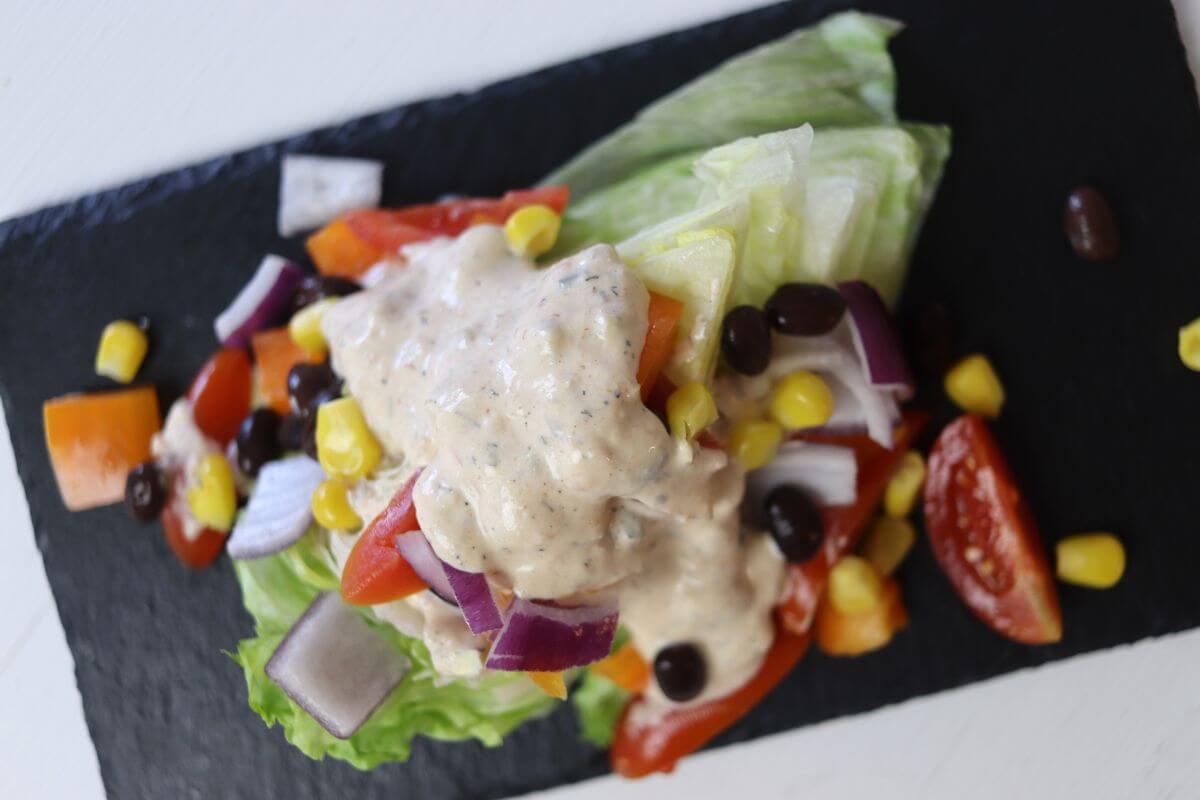 Southwest wedge salad with iceberg, black beans, corn, tomatoes, onion, and dressing.