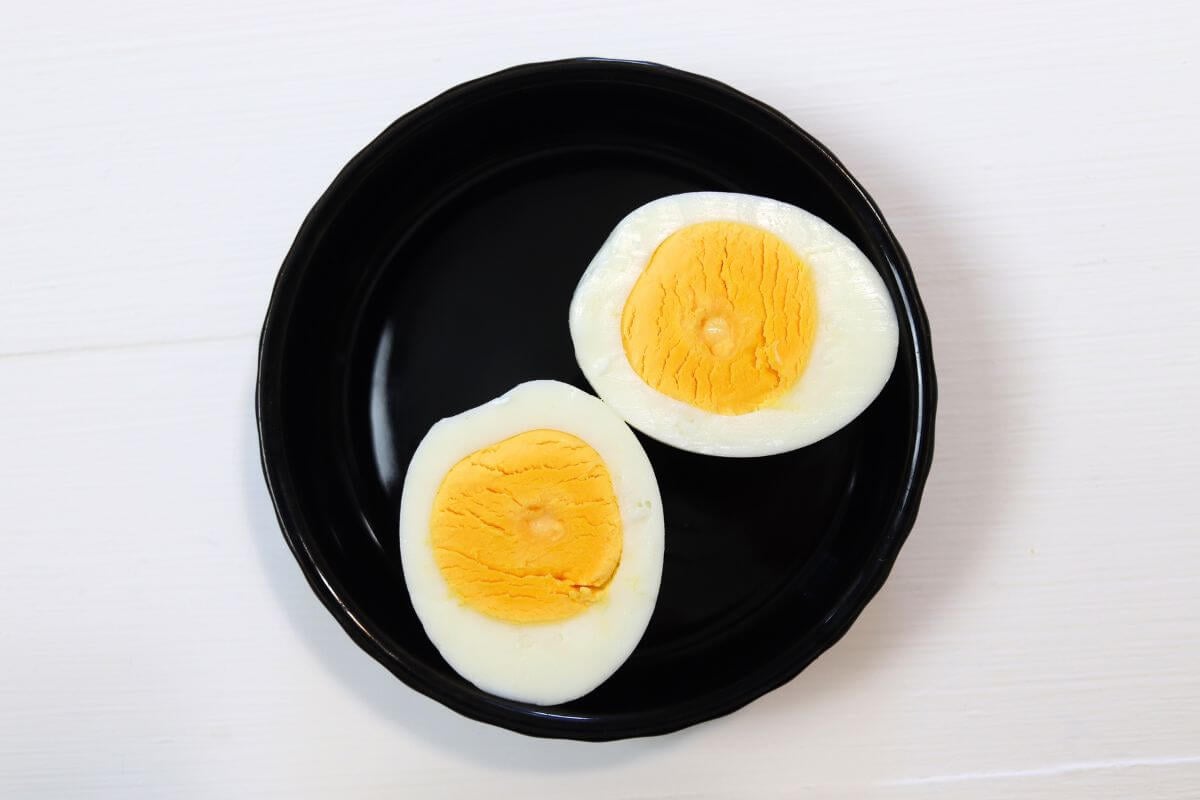 Hard cooked egg halves on a black plate with fully set yolks.