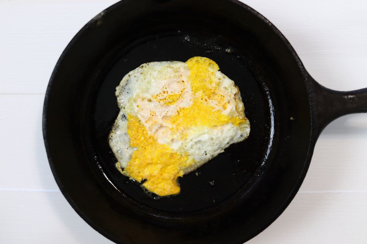 Over hard egg in a cast iron skillet on a white surface.