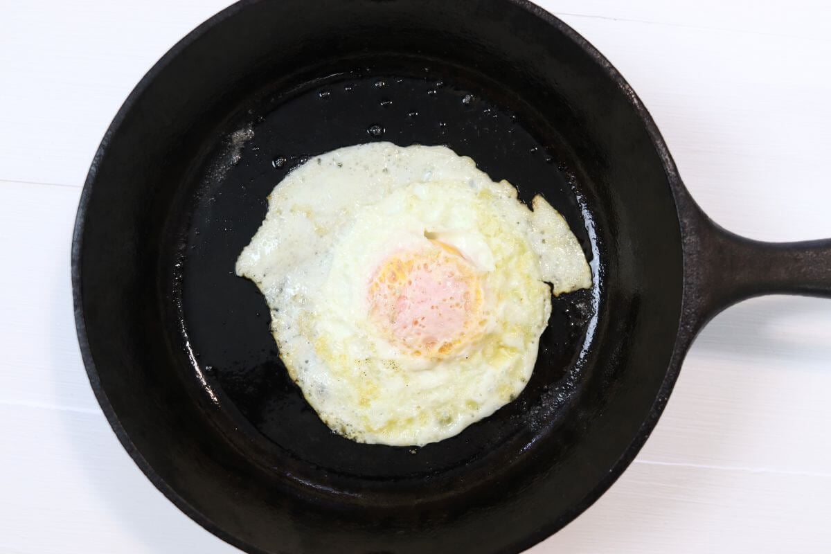 Over medium egg in a cast iron skillet on a white surface.