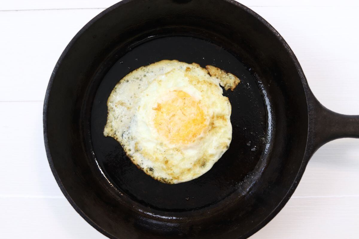 Over well egg in a cast iron skillet on a white surface.
