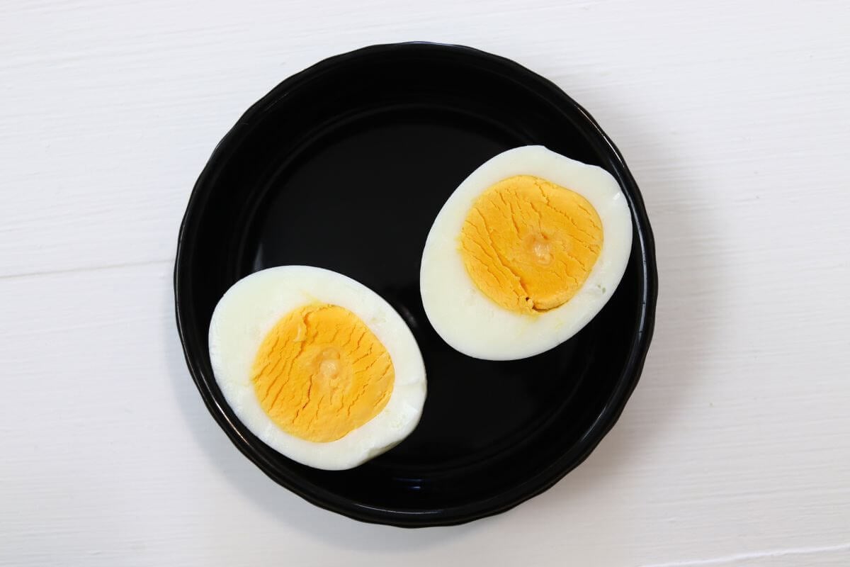 Steamed egg halves on a black dish against a white surface.