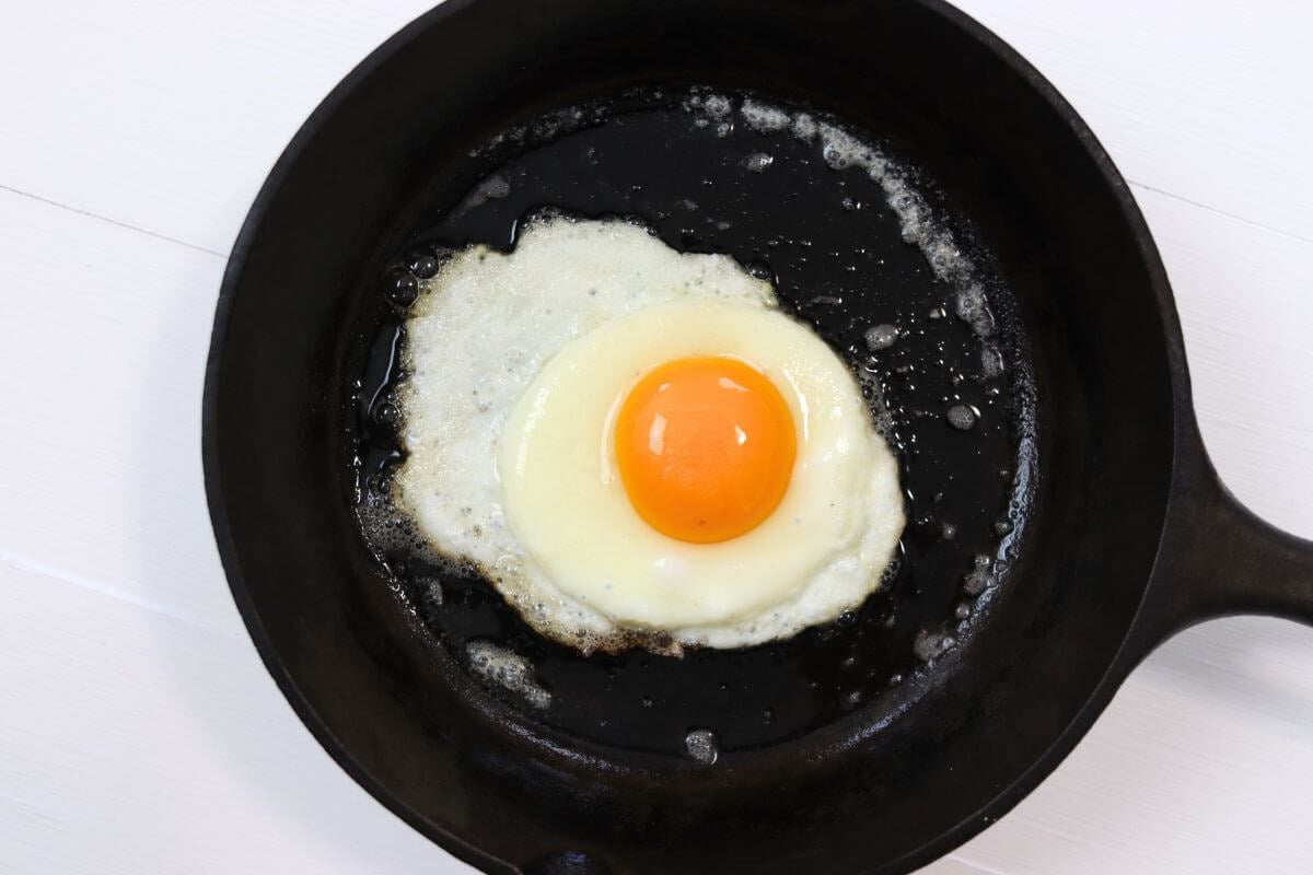 Sunny side up egg in a cast iron skillet on a white surface.