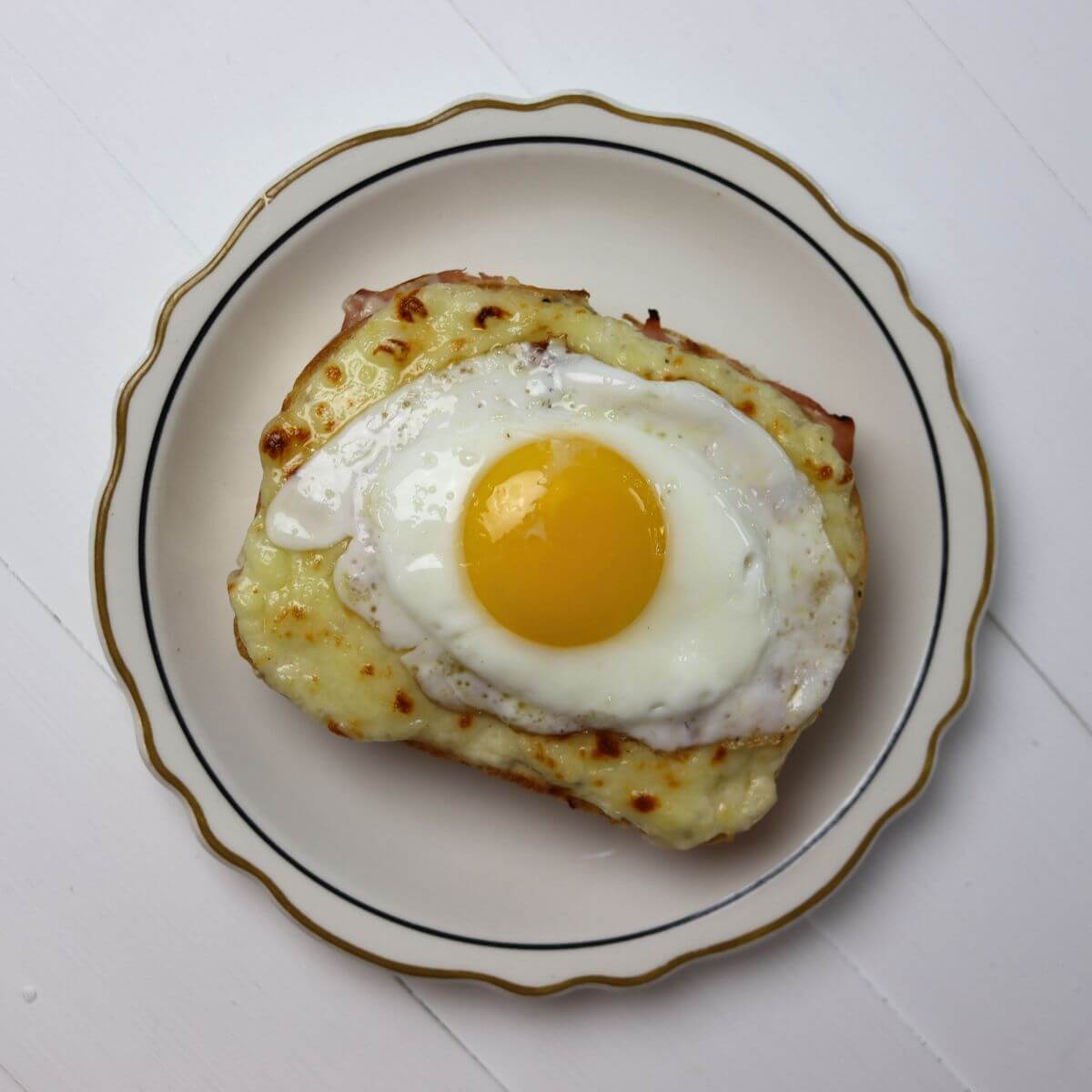 Croque madame with melted cheese and a sunny side up egg on top.