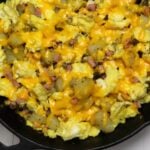Cast iron skillet with eggs, potatoes, ham, cheddar cheese, and Denver Breakfast Mess text overlay.