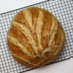 Round rye bread loaf with scored crust on a cooling rack.