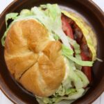 Egg BLT croissant sandwich with lettuce and tomato beside text reading “BLT Meets Breakfast Buttery Croissant Upgrade".