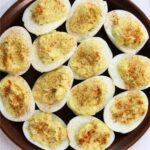 Farmhouse style deviled eggs topped with paprika and “Grandma’s Deviled Eggs” text overlay.
