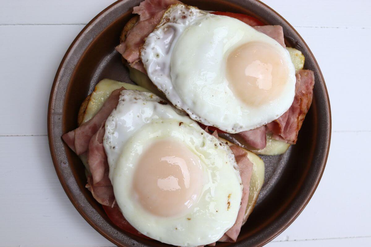 Open-faced ham breakfast sandwich with basted eggs on grilled bread.