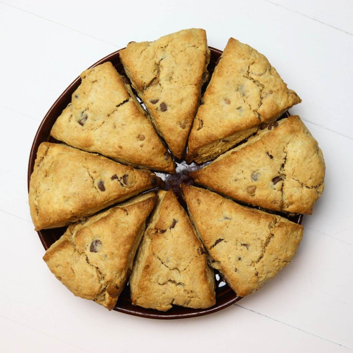 Peanut butter scones with chocolate chips arranged on a round brown plate.