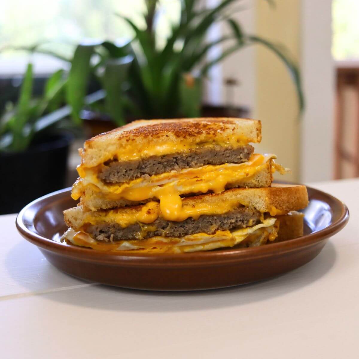 Grilled cheese sandwich with sausage, eggs, and melted cheese on a plate.