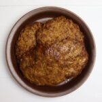 Sweet Italian sausage patties stacked in a brown bowl.