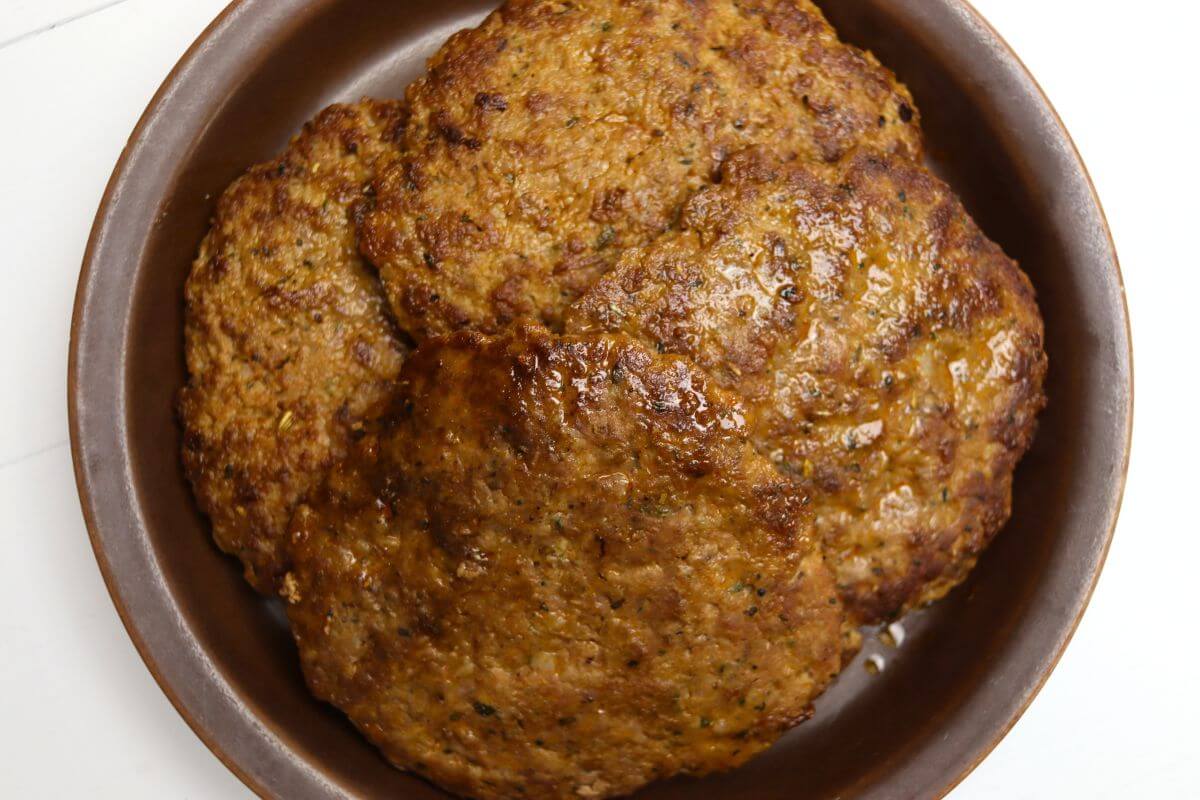 Homemade sweet Italian sausage patties in a shallow brown dish.