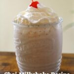 Glass of chai milkshake with whipped cream, a maraschino cherry, and the title "Chai Milkshake Recipe".