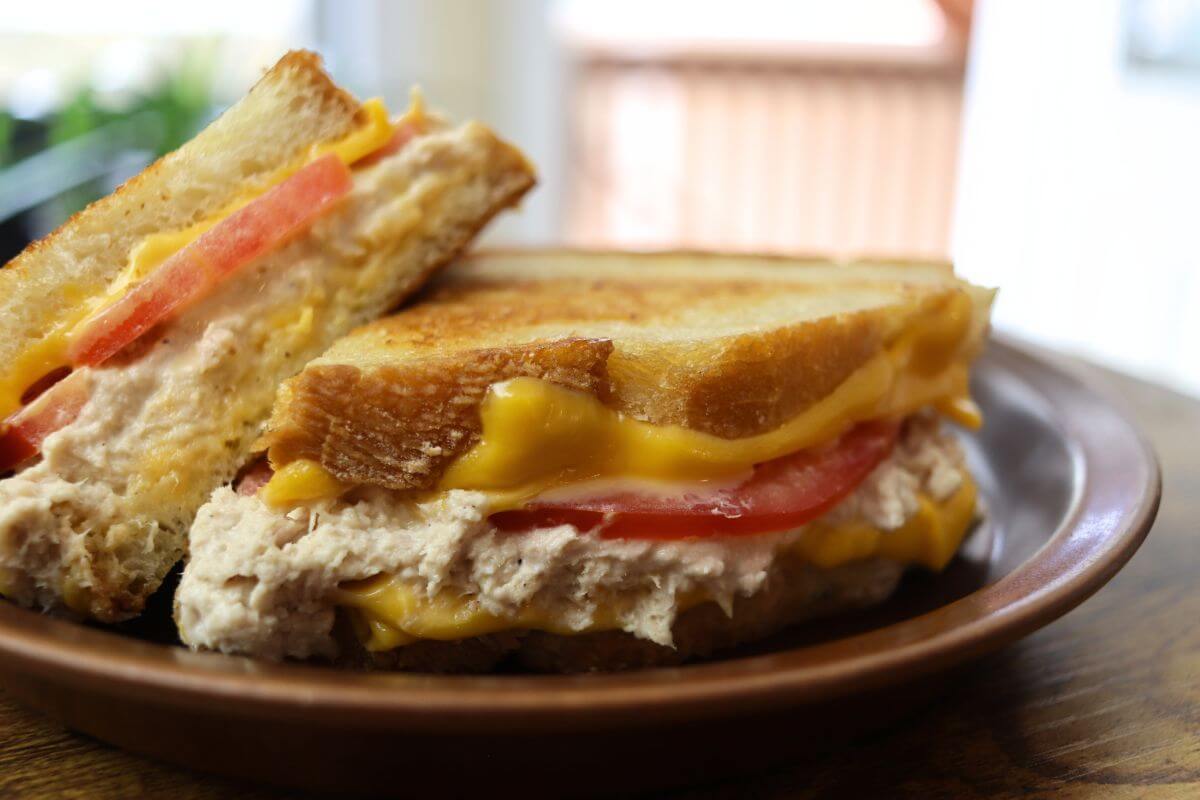Diner-style tuna melt sandwich with tomato and melted cheese on a plate.