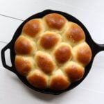 Homemade dinner rolls with browned tops baked together in a cast iron skillet.