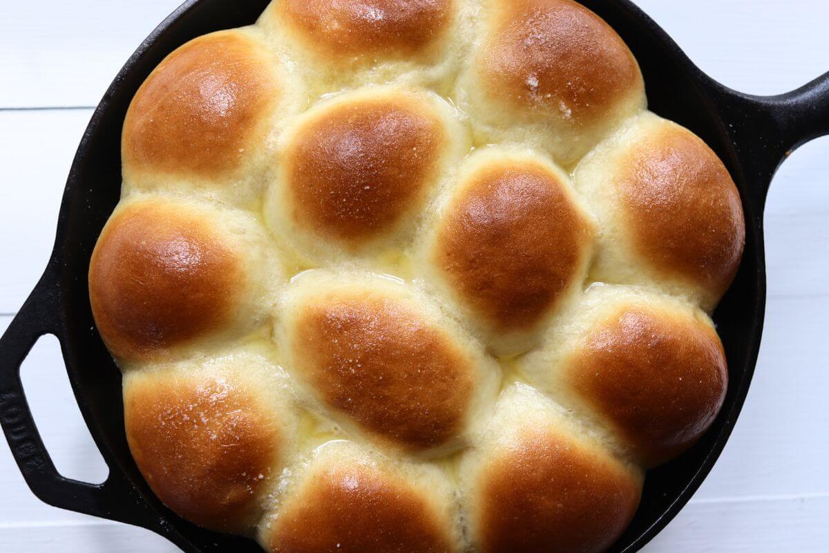 Golden brown pull-apart dinner rolls baked in a black cast iron skillet.