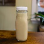 Bottle of homemade honey vanilla coffee creamer on a wooden counter.