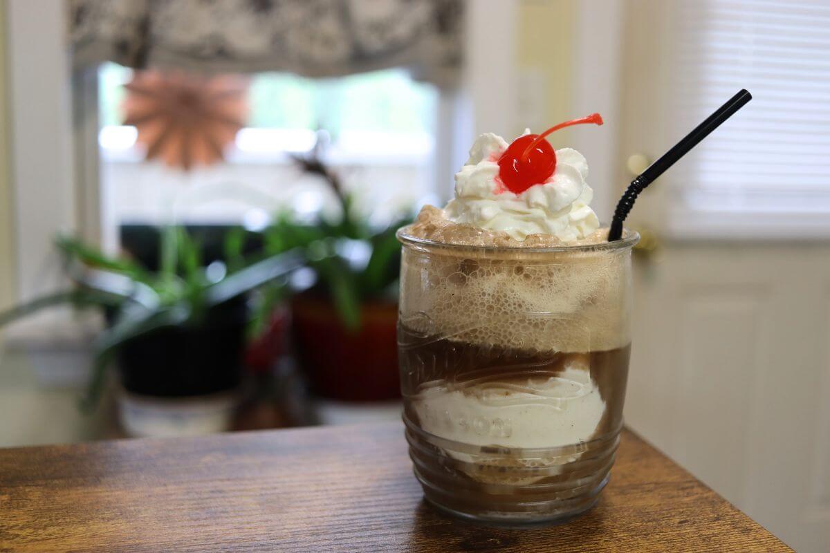 Old fashioned ice cream float topped with whipped cream and cherry.