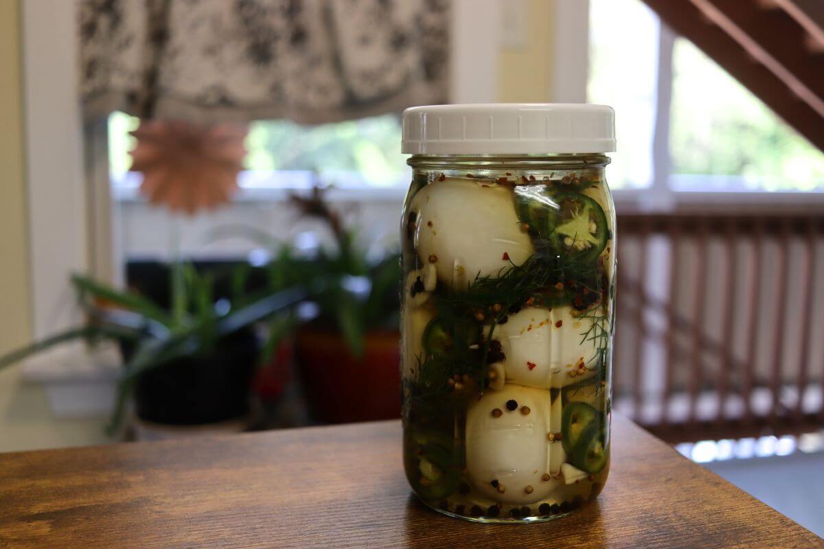 Mason jar filled with eggs, jalapeño slices, dill, and peppercorns.