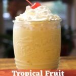 Tropical fruit milkshake topped with whipped cream and a maraschino cherry. Text overlay: "Tropical Fruit Milkshake Recipe".
