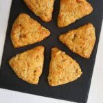 Apple cheddar scones arranged on a black slate serving board with the title "Apple Cheddar Scones".