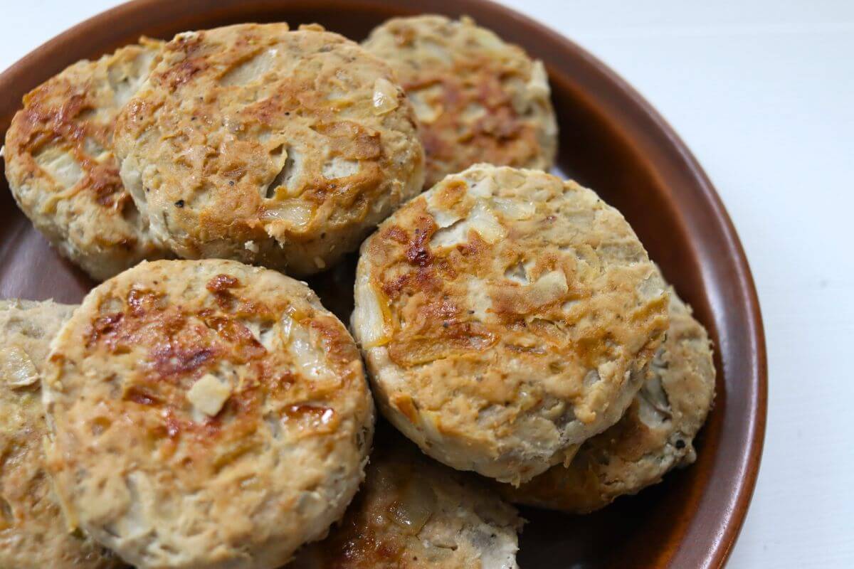 Browned apple pork sausage patties stacked on a brown plate.