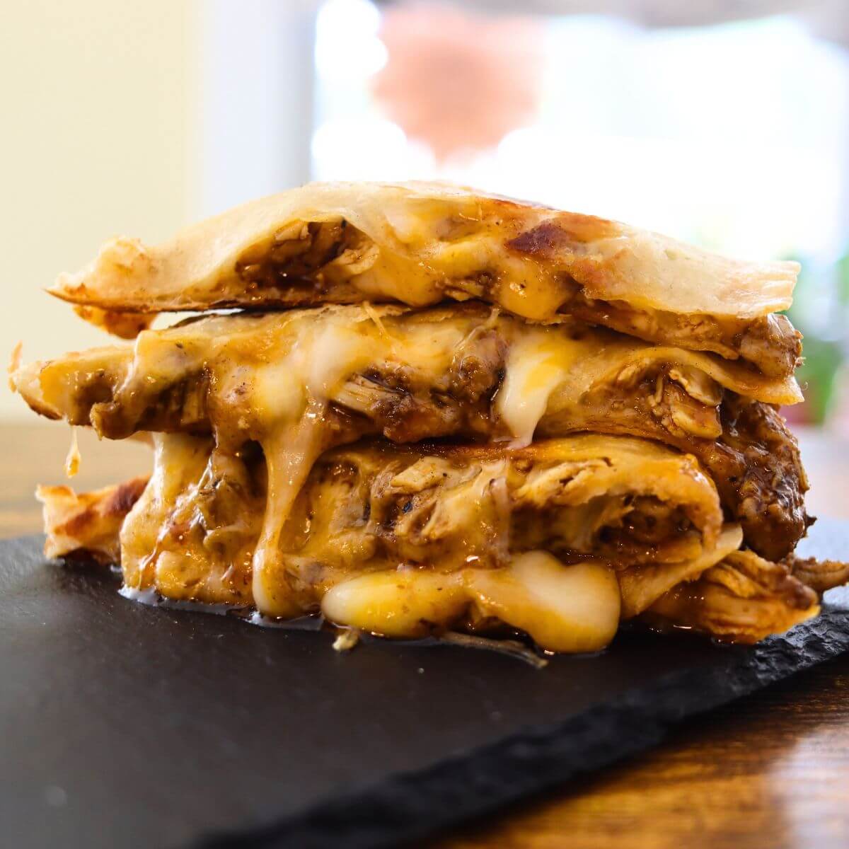 Stack of cheesy Cajun chicken quesadilla wedges with melted cheese stretching between the layers.