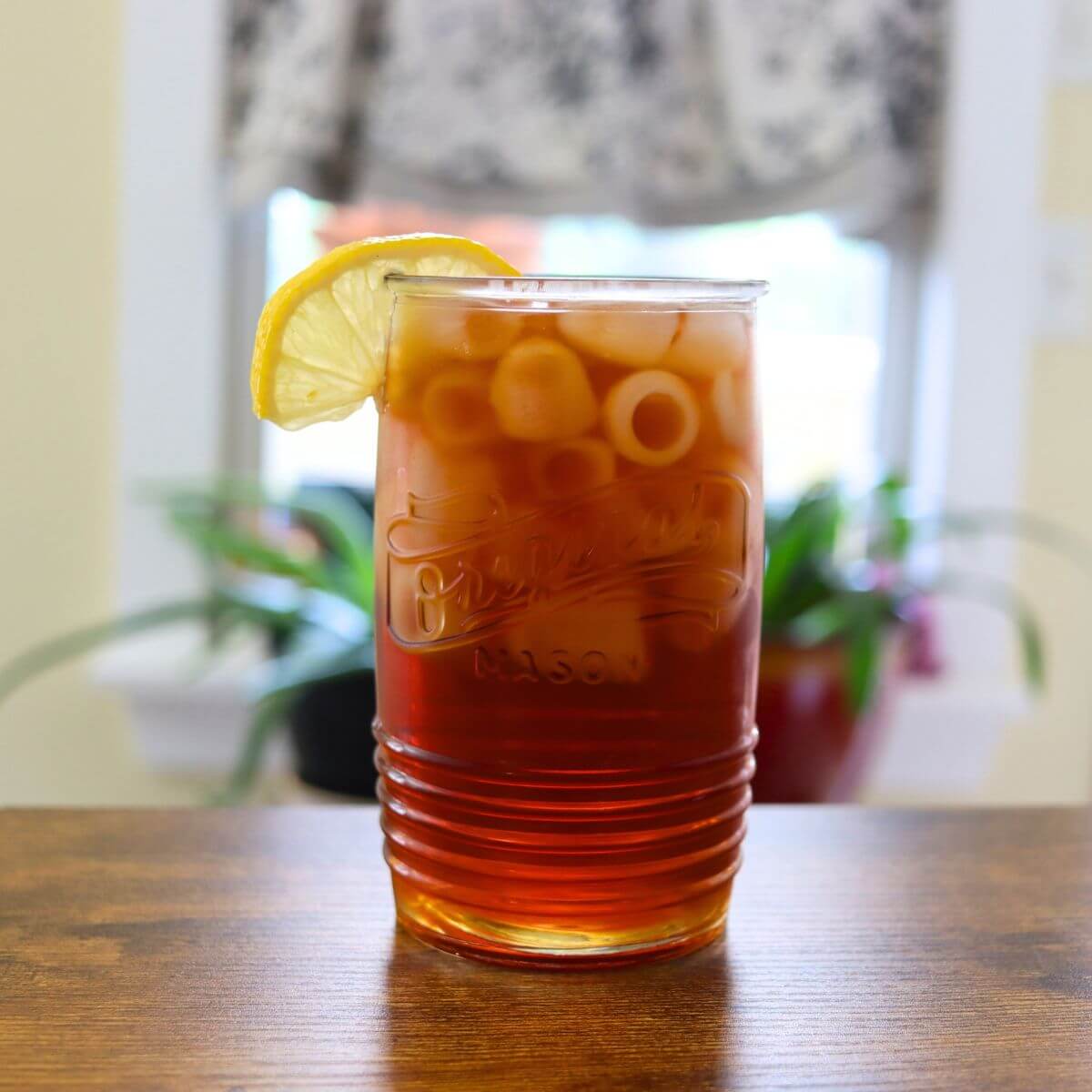 Glass of fresh brewed iced tea with ice cubes and a lemon slice.