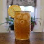 Glass of homemade Arnold Palmer over ice with a lemon slice on the rim.