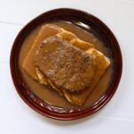 Hot hamburger sandwich topped with brown gravy and served on two slices of white bread.
