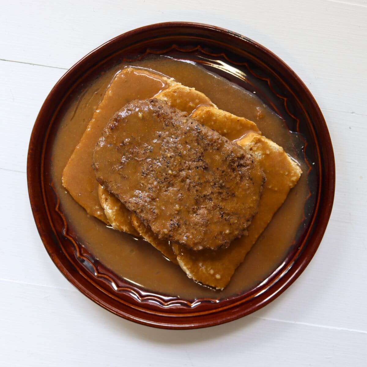 Hot hamburger sandwich topped with brown gravy and served on two slices of white bread.
