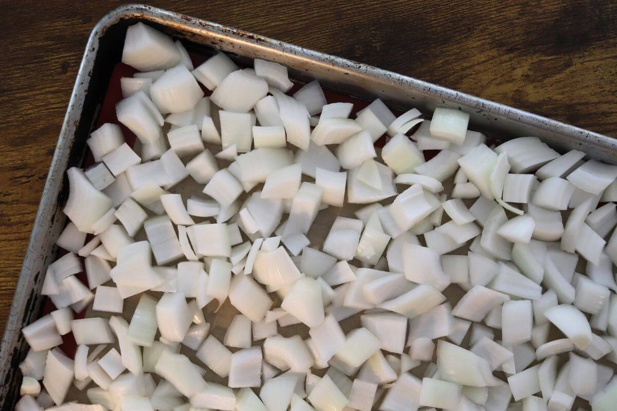 Diced white onions arranged on a baking sheet for flash freezing.