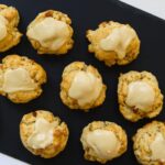 Maple walnut scones with maple icing on a black serving board with the text "Maple Walnut Scones".