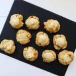Maple walnut scones topped with maple icing arranged on a black serving board.