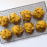Eight pumpkin cranberry scones cooling on a black wire rack.