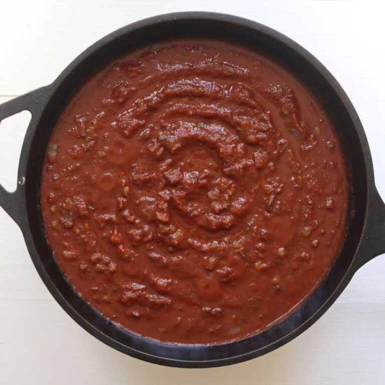 Thick red pasta sauce in a black cast iron Dutch oven.
