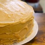 Vanilla caramel cake with homemade caramel frosting on a white cake plate. Text overlay reads "Vanilla Caramel Cake".