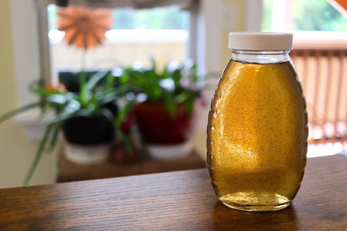 Glass bottle filled with homemade vanilla simple syrup with vanilla bean specks in it.